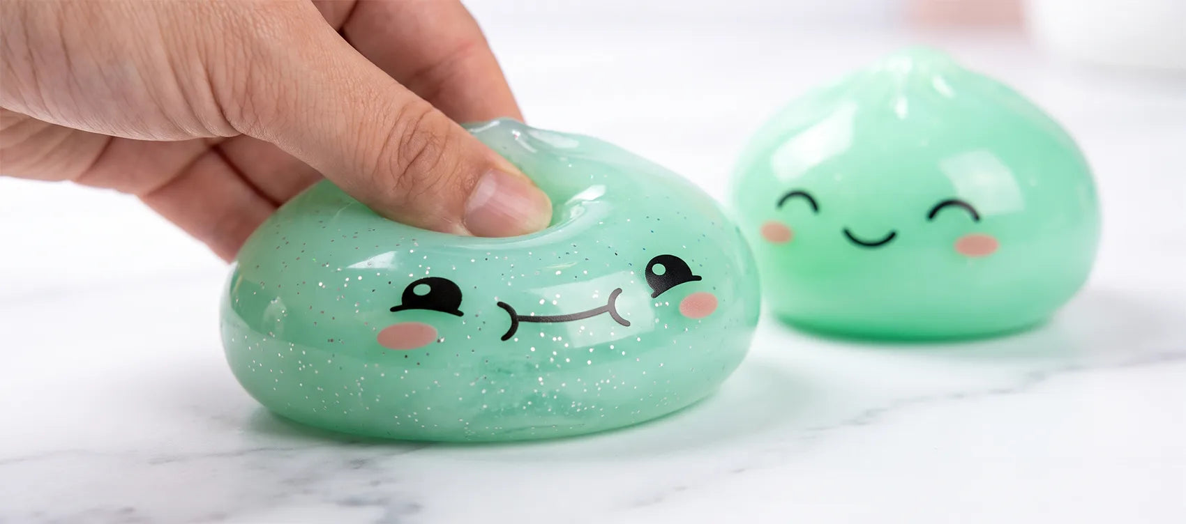 Mint green dumpling squishy squashed flat under a finger beside an identical one fully rebounded
